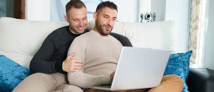 Same sex couple sitting on couch with laptop